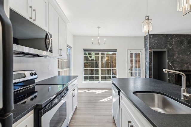 7525 Holly Hill Dr Unit 17, Dallas, TX 75231 - kitchen featuring appliances with stainless steel finishes, a chandelier, a sink, and light wood-type flooring