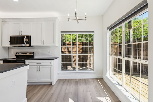 7525 Holly Hill Dr Unit 17, Dallas, TX 75231 - kitchen with stainless steel appliances, a chandelier, dark countertops, and light wood-style flooring