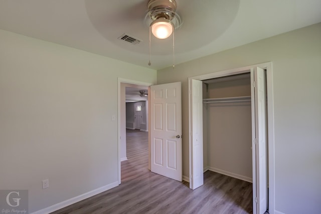 unfurnished bedroom featuring wood finished floors, baseboards, a closet, and ceiling fan