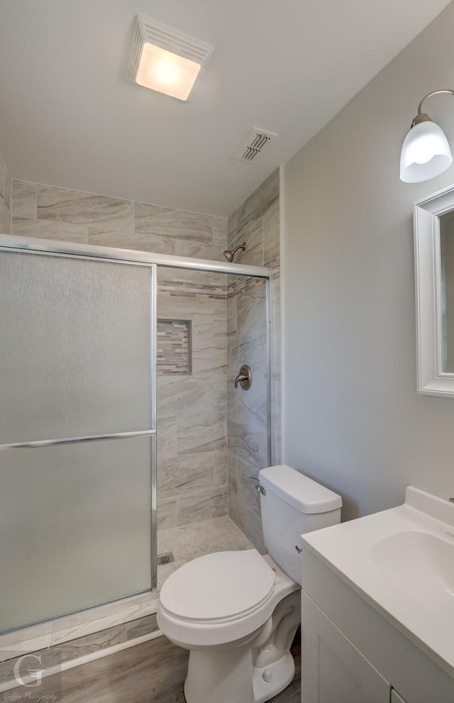 bathroom featuring a shower stall, toilet, and vanity