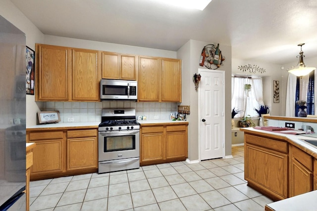 1942 Garrison Way, Garland, TX 75040 - kitchen featuring appliances with stainless steel finishes, light countertops, backsplash, light tile patterned floors, and hanging light fixtures