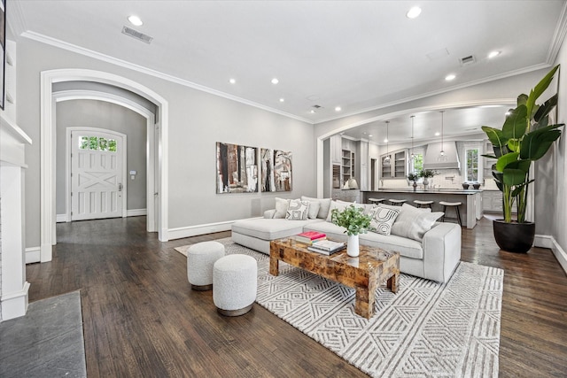 living room featuring arched walkways, recessed lighting, dark wood-style floors, baseboards, and ornamental molding