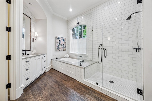 full bath featuring a shower stall, ornamental molding, wood finished floors, vanity, and a garden tub
