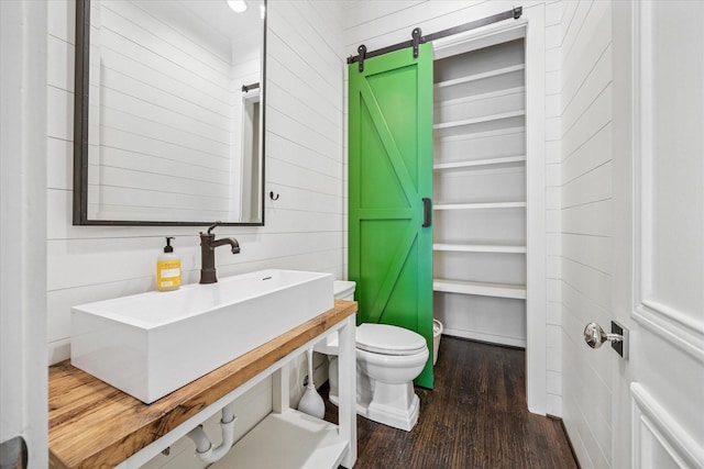 bathroom featuring wood finished floors, toilet, and a sink