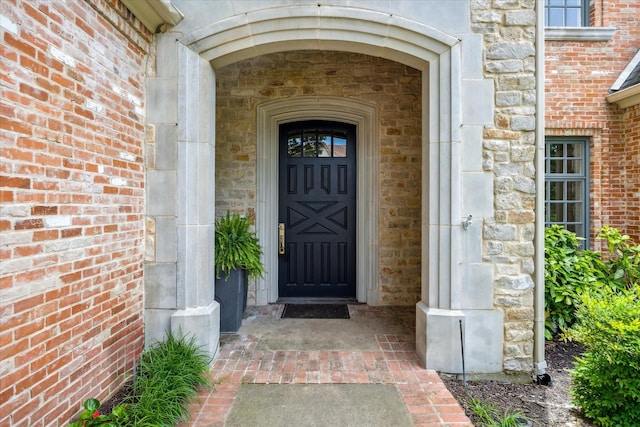entrance to property featuring stone siding and brick siding