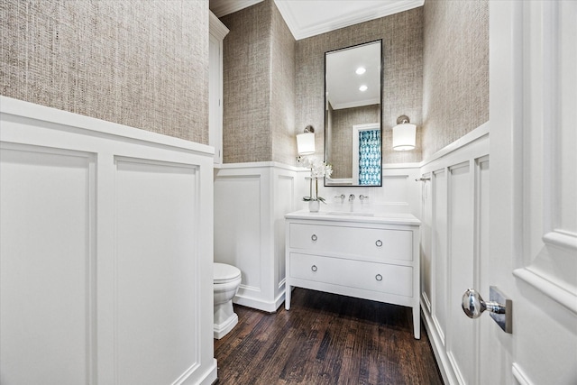 bathroom featuring crown molding, a decorative wall, toilet, a wainscoted wall, and wood finished floors