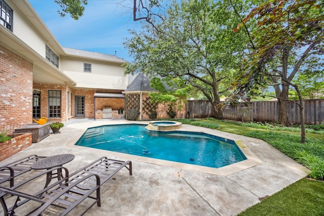 view of swimming pool featuring a patio, a fenced backyard, and a pool with connected hot tub