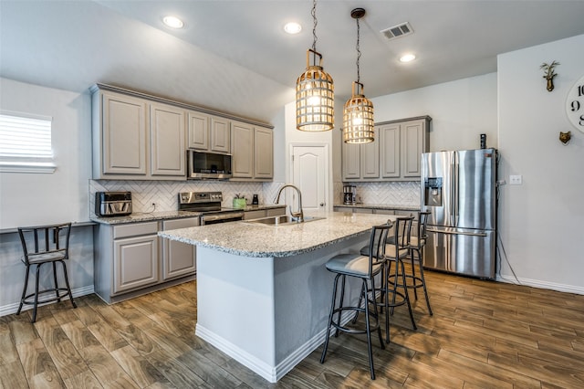 5712 Demi Sec Dr, Mckinney, TX 75070 - kitchen featuring stainless steel appliances, gray cabinets, a sink, a kitchen bar, and tasteful backsplash