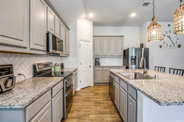 5712 Demi Sec Dr, Mckinney, TX 75070 - kitchen with stainless steel appliances, gray cabinetry, a sink, an island with sink, and recessed lighting