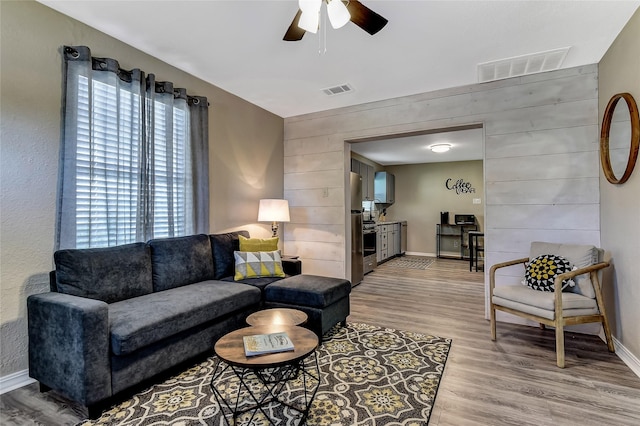401 W Acheson St, Denison, TX 75020 - living area featuring a ceiling fan, light wood-style flooring, baseboards, and wooden walls