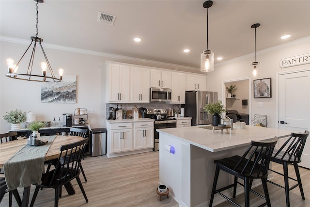 816 Killam Dr, Temple, TX 76502 - kitchen with appliances with stainless steel finishes, crown molding, white cabinets, a chandelier, and decorative backsplash