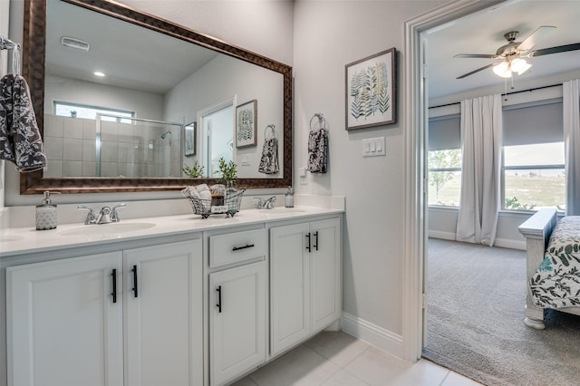bathroom with a shower stall, double vanity, a ceiling fan, baseboards, and ensuite bath