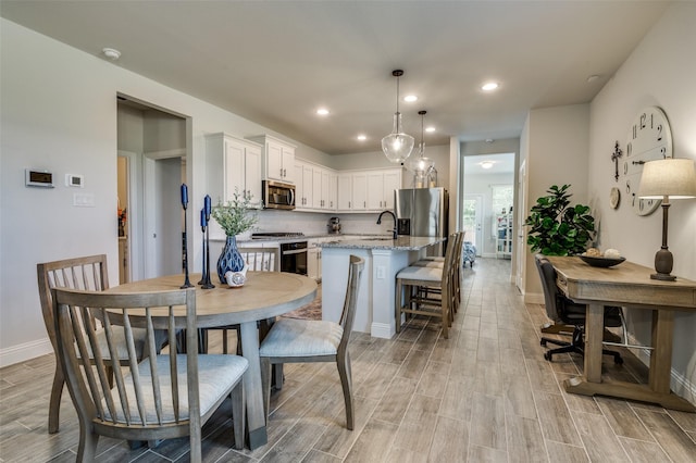 dining room with light wood-style flooring, baseboards, and recessed lighting