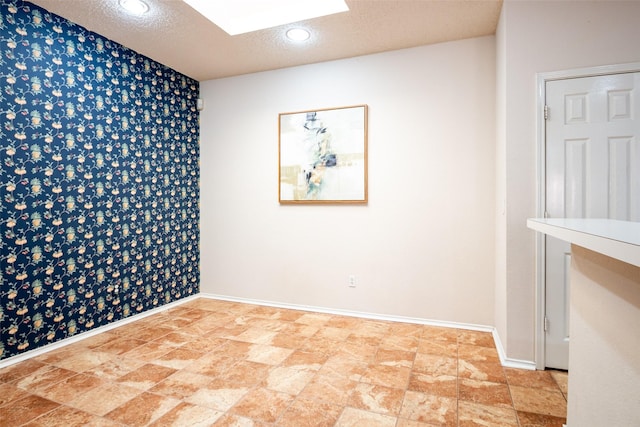 3104 Ridge Hollow Dr, Plano, TX 75023 - spare room with an accent wall, baseboards, stone finish floors, a skylight, and a textured ceiling