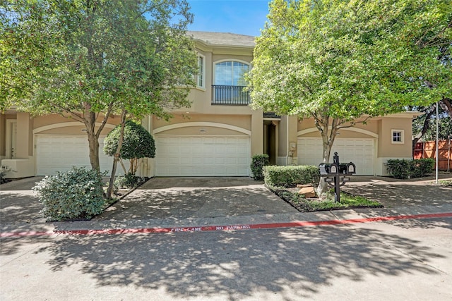 view of front facade with concrete driveway, stucco siding, a garage, and a balcony