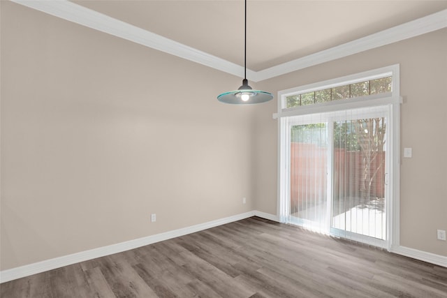 unfurnished dining area featuring wood finished floors, baseboards, and crown molding