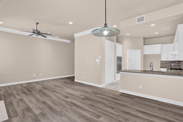 unfurnished living room with ceiling fan, a sink, recessed lighting, light wood finished floors, and baseboards