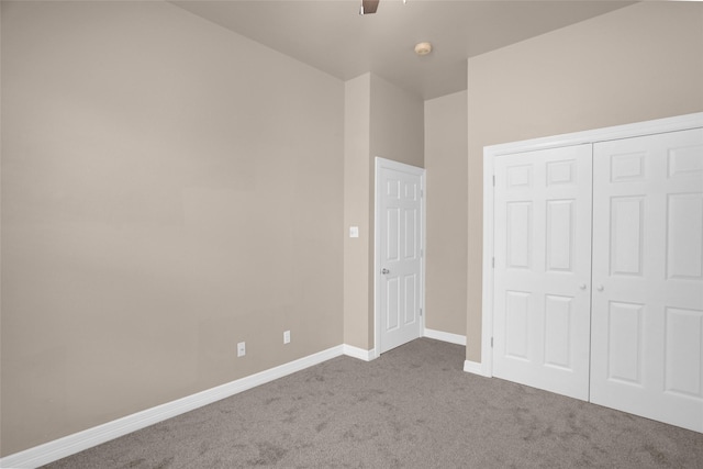 unfurnished bedroom featuring carpet, baseboards, a closet, and a ceiling fan