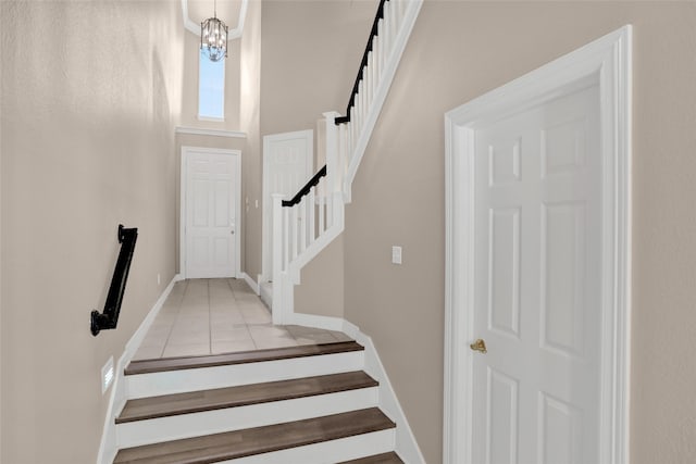 stairs with tile patterned flooring, a towering ceiling, and baseboards