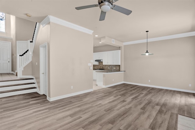 unfurnished living room featuring light wood-style flooring, baseboards, recessed lighting, stairs, and crown molding