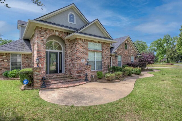 2116 Landau Ln, Bossier City, LA 71111 - traditional-style home with stucco siding, brick siding, a front lawn, and roof with shingles