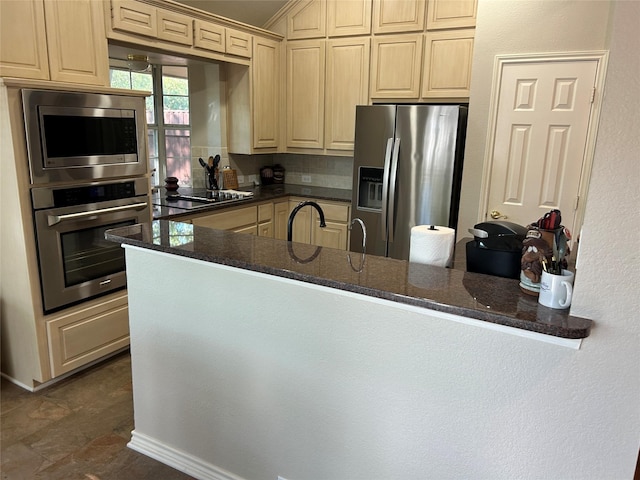 5900 Sandhill Cir, The Colony, TX 75056 - kitchen featuring stainless steel appliances, a peninsula, dark stone counters, crown molding, and light brown cabinets
