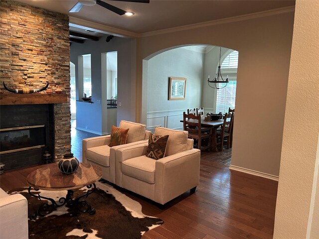 5900 Sandhill Cir, The Colony, TX 75056 - living room featuring arched walkways, dark wood-style flooring, a ceiling fan, crown molding, and a fireplace