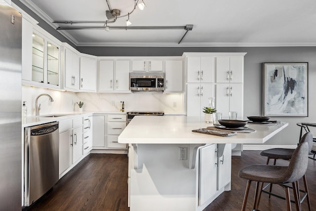 6211 W NW Unit 701, Dallas, TX 75225 - kitchen with appliances with stainless steel finishes, a sink, dark wood-type flooring, white cabinets, and a center island
