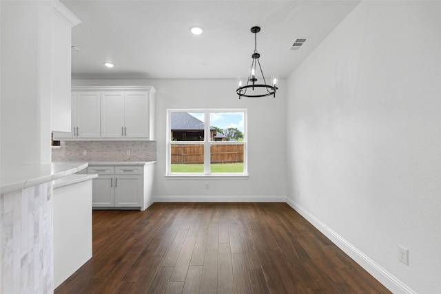 unfurnished dining area featuring a chandelier, baseboards, dark wood-type flooring, and recessed lighting