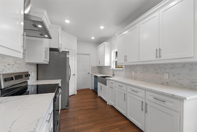 kitchen featuring stainless steel appliances, a sink, white cabinets, dark wood finished floors, and wall chimney exhaust hood
