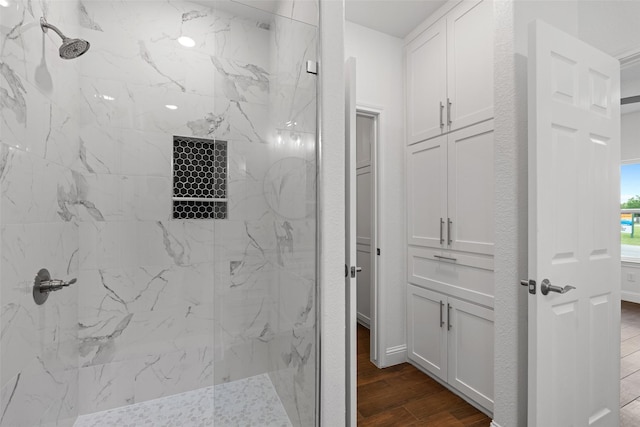 full bath with a marble finish shower and wood finished floors