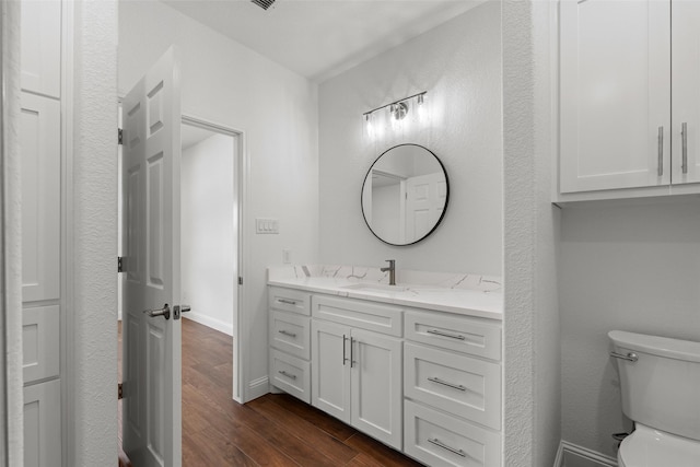 bathroom featuring wood finished floors, toilet, vanity, and baseboards