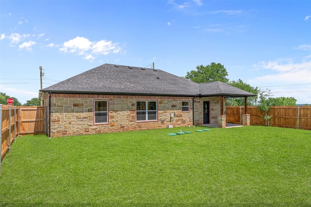 rear view of property with roof with shingles, stone siding, and a patio area