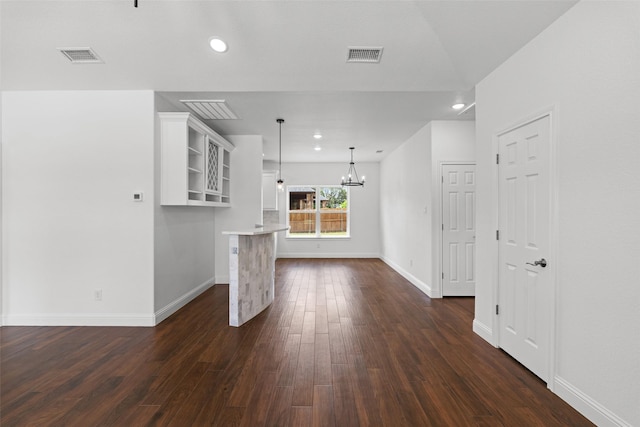 unfurnished living room featuring a chandelier, dark wood finished floors, recessed lighting, and baseboards
