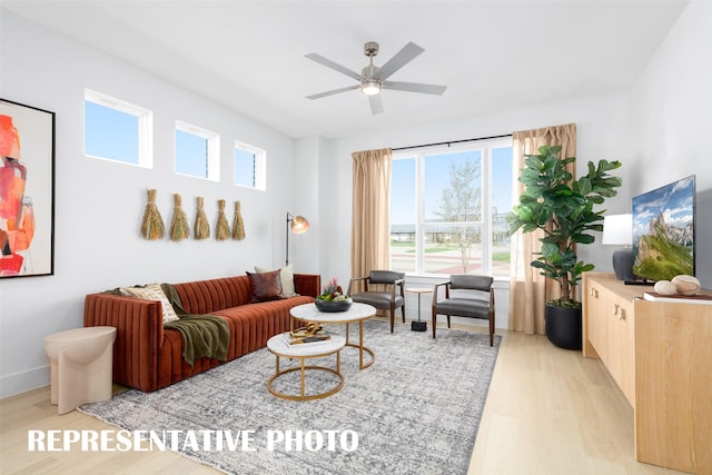 living area featuring light wood-style floors, plenty of natural light, and a ceiling fan