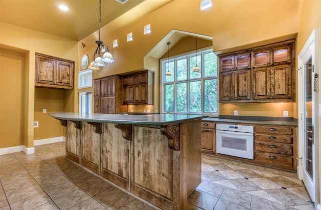 711 Pearl Cv, Oak Point, TX 75068 - kitchen featuring oven, dark countertops, a breakfast bar, a center island, and decorative light fixtures