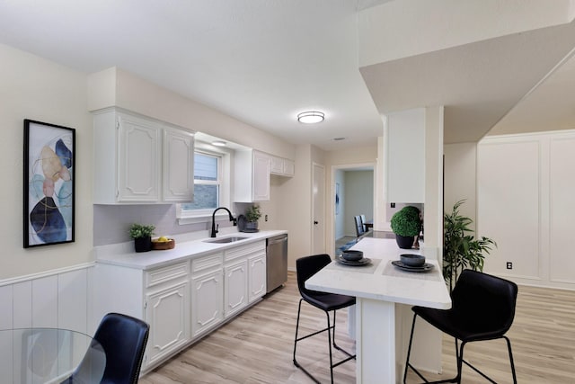 2809 Valley Ridge Dr, Richardson, TX 75080 - kitchen with a sink, stainless steel dishwasher, a kitchen bar, light wood-type flooring, and a decorative wall