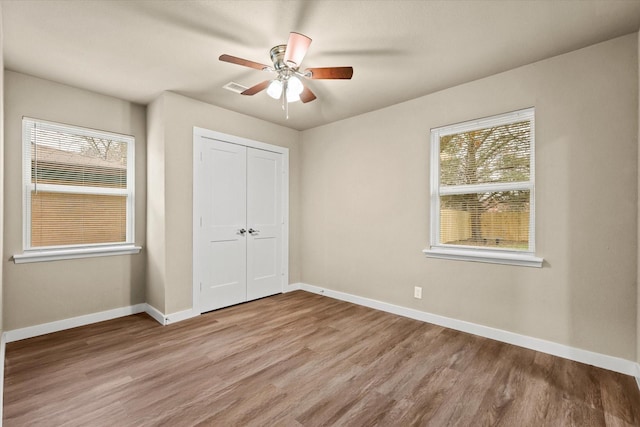 612 S Mills Dr, Euless, TX 76040 - unfurnished bedroom with multiple windows, light wood finished floors, and baseboards