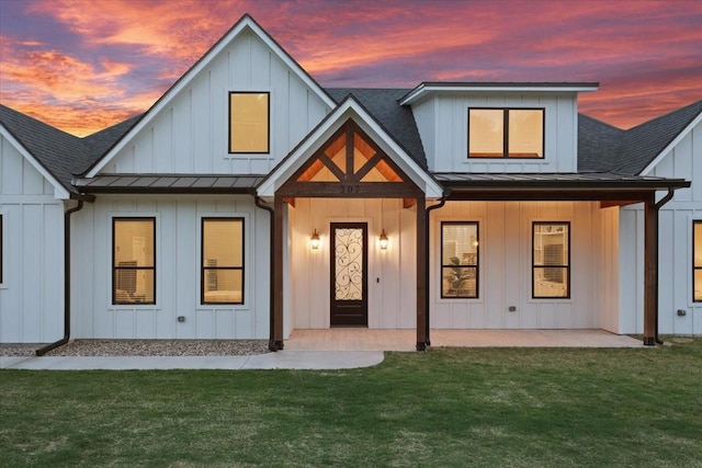 207 Merrifield Dr, Woodway, TX 76712 - back of property at dusk with a standing seam roof, a shingled roof, a yard, and metal roof