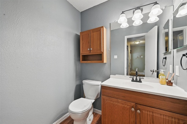 4841 Woodstock Dr, Fort Worth, TX 76137 - bathroom with toilet, baseboards, wood finished floors, a textured wall, and vanity