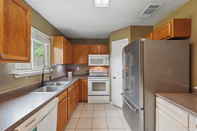 4841 Woodstock Dr, Fort Worth, TX 76137 - kitchen with white appliances, a sink, a textured ceiling, brown cabinets, and light tile patterned floors