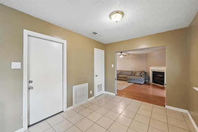 4841 Woodstock Dr, Fort Worth, TX 76137 - foyer entrance featuring a textured ceiling, a tile fireplace, a ceiling fan, light tile patterned floors, and baseboards