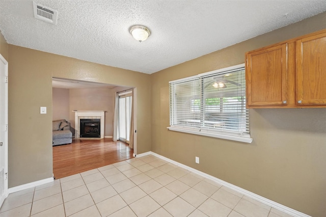 4841 Woodstock Dr, Fort Worth, TX 76137 - unfurnished living room featuring a textured ceiling, a fireplace, light tile patterned floors, and baseboards