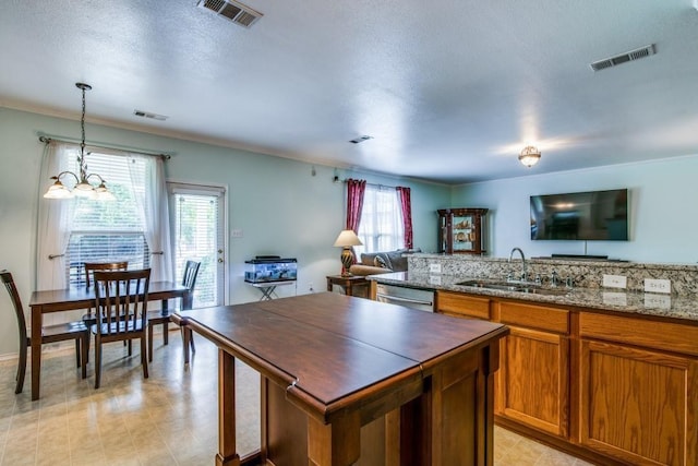 3815 Pinebluff Ln, Rockwall, TX 75032 - kitchen with a sink, dishwasher, brown cabinetry, open floor plan, and decorative light fixtures