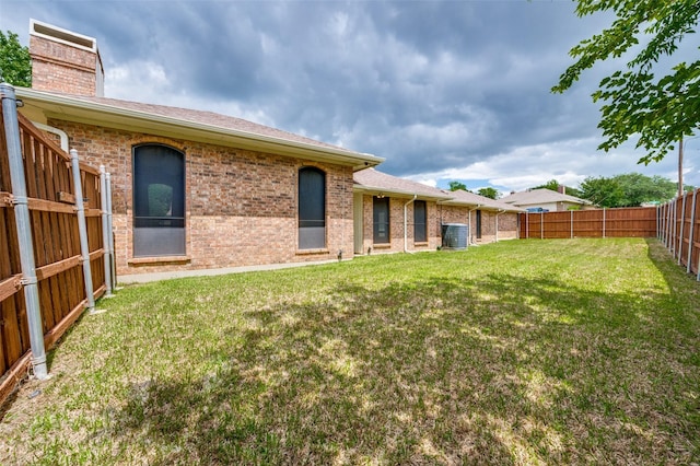 1600 Railhead Pl, Carrollton, TX 75007 - back of house with central AC, brick siding, a chimney, and a shingled roof