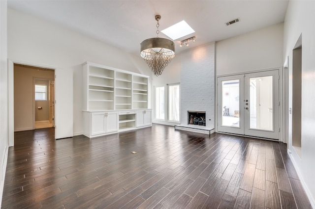 1600 Railhead Pl, Carrollton, TX 75007 - unfurnished living room with a towering ceiling, a chandelier, a skylight, dark wood-style floors, and a large fireplace