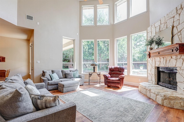 12332 Green Ash Dr, Fort Worth, TX 76244 - living area featuring a towering ceiling, a stone fireplace, wood finished floors, and baseboards