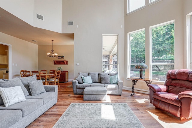 12332 Green Ash Dr, Fort Worth, TX 76244 - living area featuring a towering ceiling, healthy amount of natural light, a chandelier, light wood-style floors, and baseboards