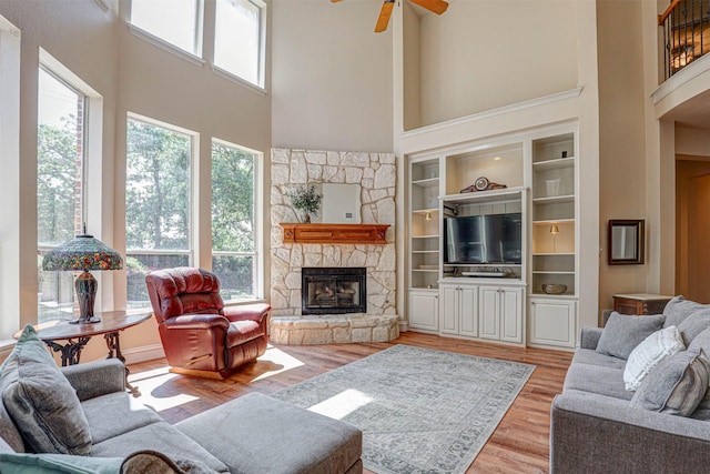 12332 Green Ash Dr, Fort Worth, TX 76244 - living room with a towering ceiling, a stone fireplace, ceiling fan, light wood finished floors, and built in shelves