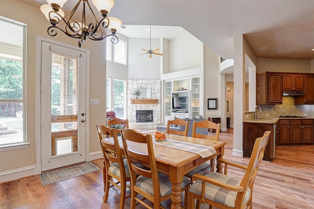 12332 Green Ash Dr, Fort Worth, TX 76244 - dining area featuring plenty of natural light, ceiling fan, light wood-style flooring, a stone fireplace, and a towering ceiling